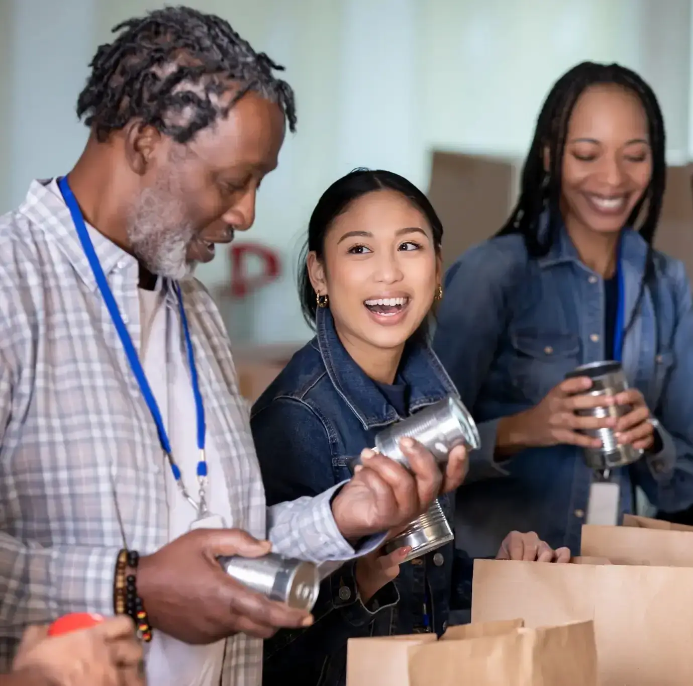 People putting cans of food into paper bags and smiling.